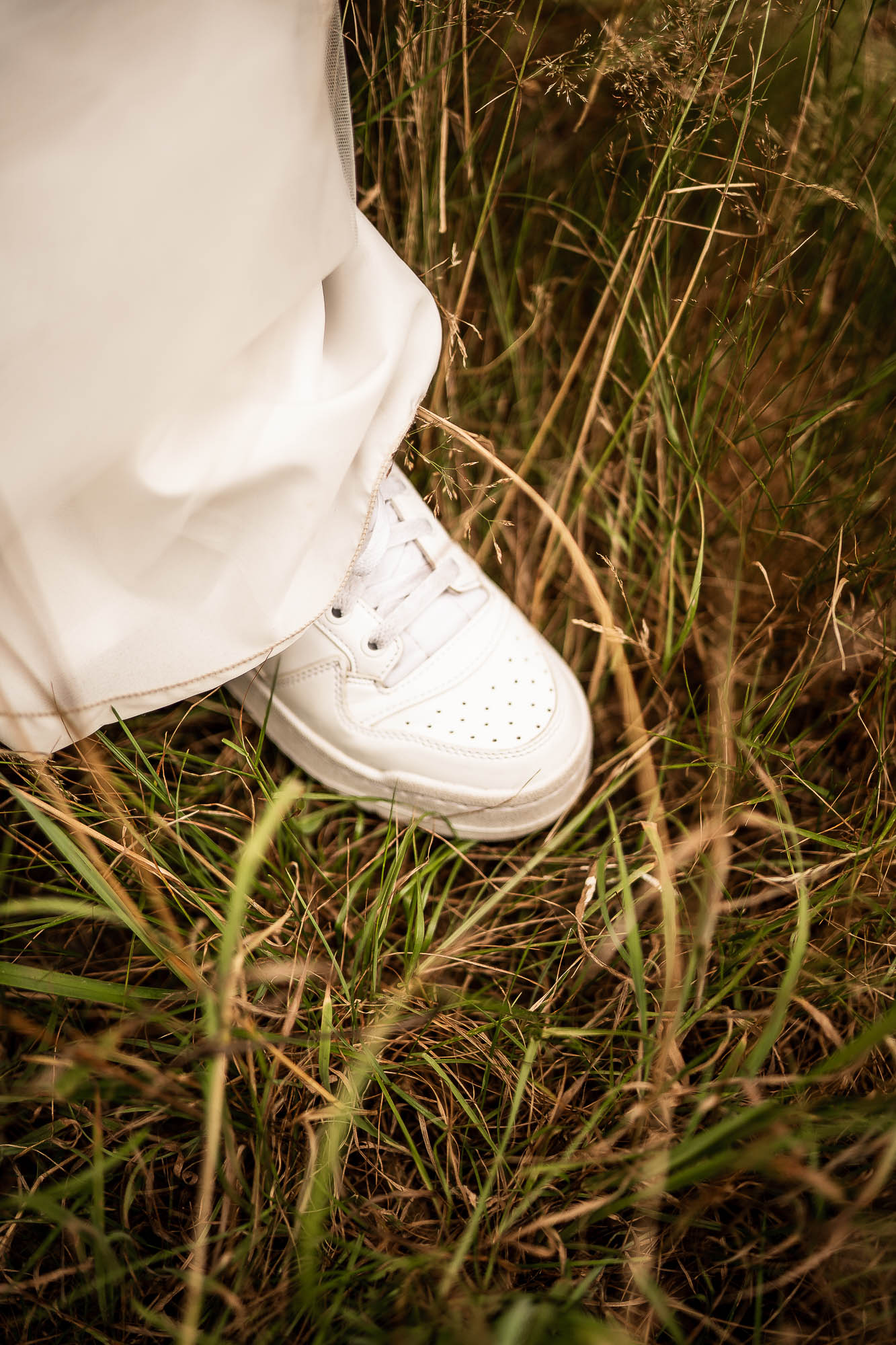 Bride wearing white trainers beneath wedding dress at Wonwood Barton